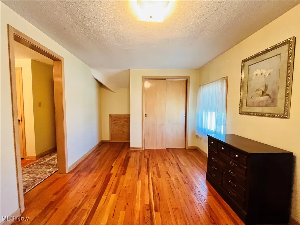 Unfurnished bedroom with light wood-style floors, a textured ceiling, and a closet