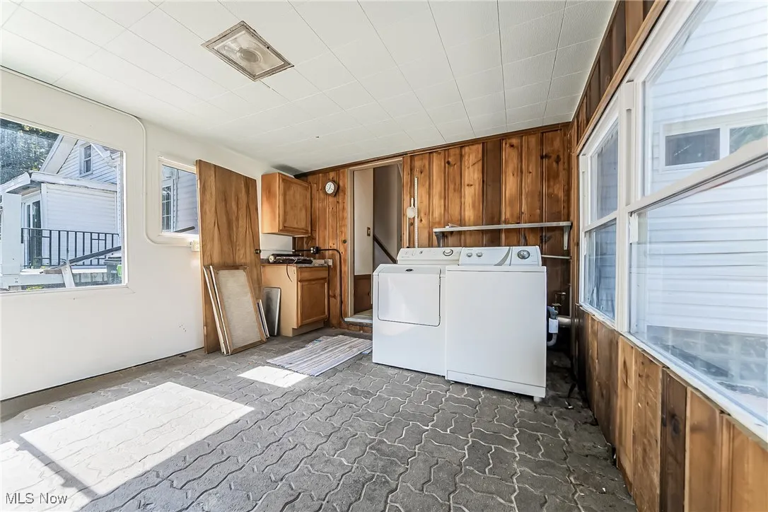 Breezeway with wooden walls and independent washer and dryer