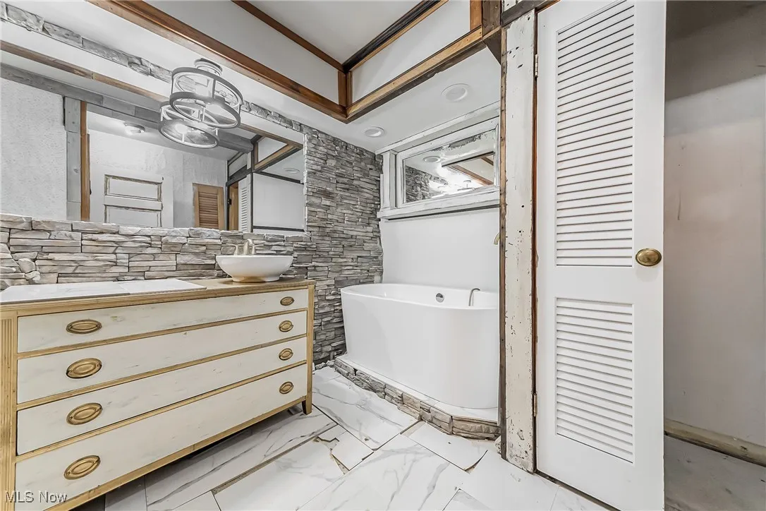 Unfinished bathroom featuring ornamental molding, a washtub, and vanity