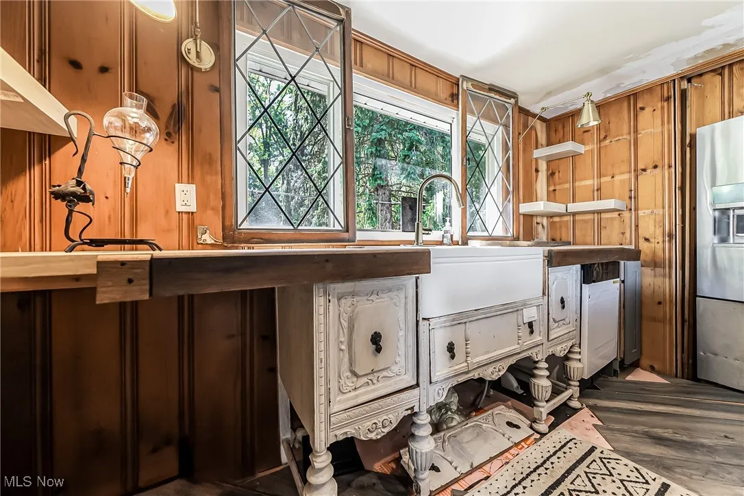 Unfinished kitchen with wooden walls, dark hardwood / wood-style floors, and sink