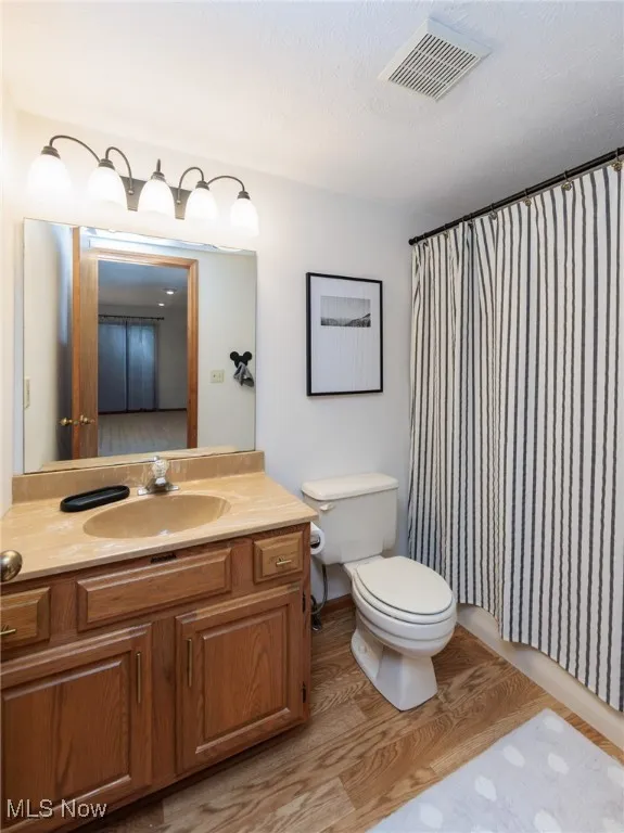 Second floor full bathroom featuring light wood finished floors, vanity, curtained shower, and a textured ceiling