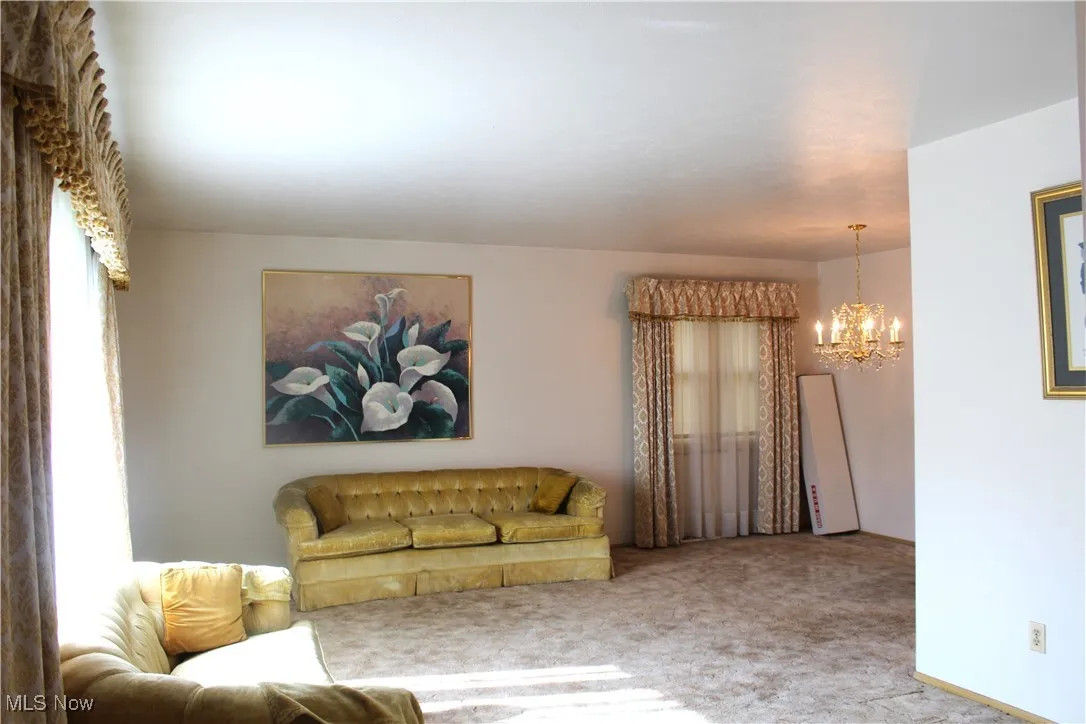 Carpeted living area featuring a chandelier