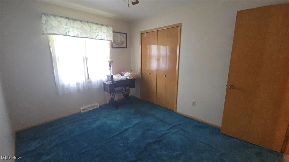 Unfurnished bedroom with carpet, a closet, and a ceiling fan