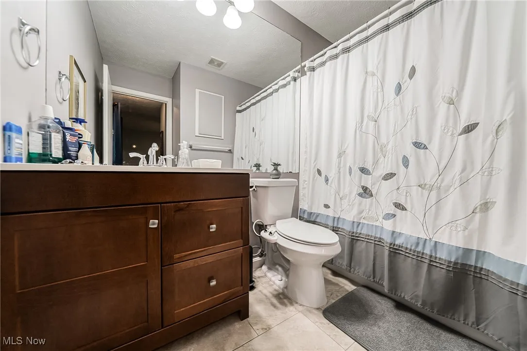 Full bathroom featuring vanity, a textured ceiling, and light tile patterned floors