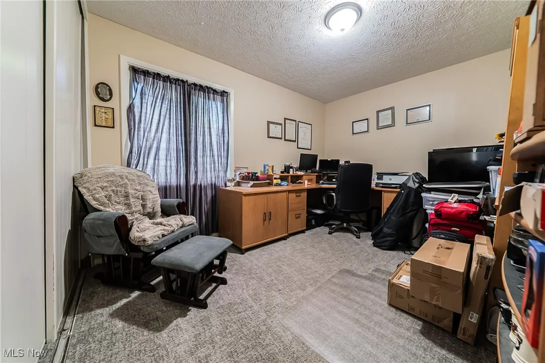 Office space with light colored carpet and a textured ceiling