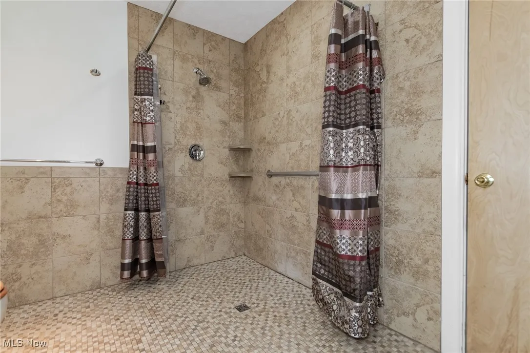 Full bathroom featuring tiled shower and tile walls