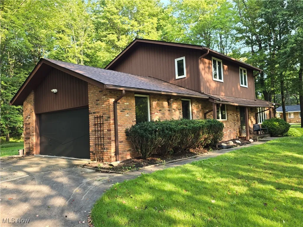 View of front of house with brick siding, a garage, driveway, and a front yard