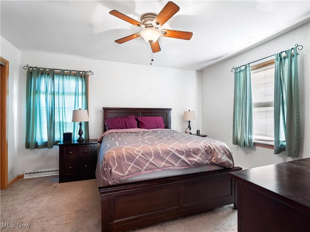 Bedroom with light carpet, multiple windows, and ceiling fan