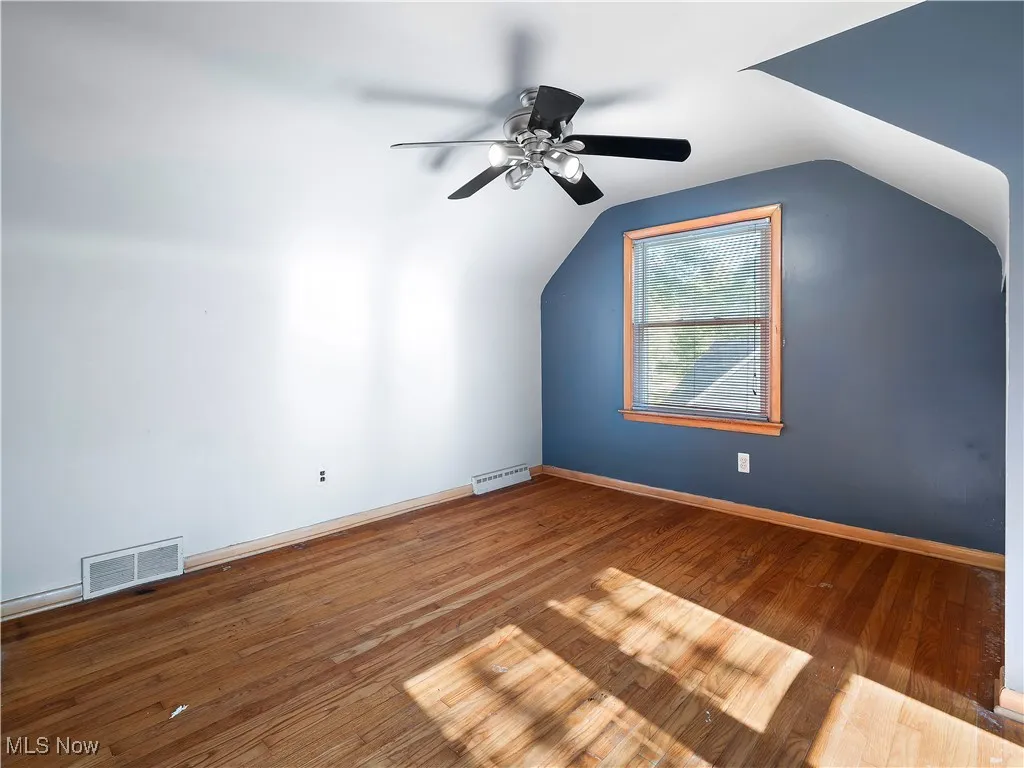 Additional living space with hardwood / wood-style floors, vaulted ceiling, and ceiling fan