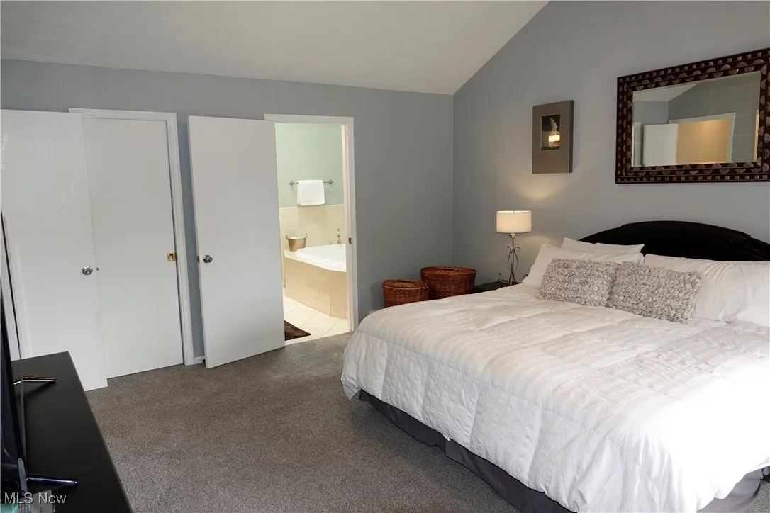 Bedroom with lofted ceiling, carpet floors, and ensuite bath
