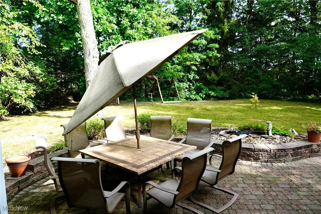 View of patio / terrace with a fire pit, outdoor dining space, and view of wooded area