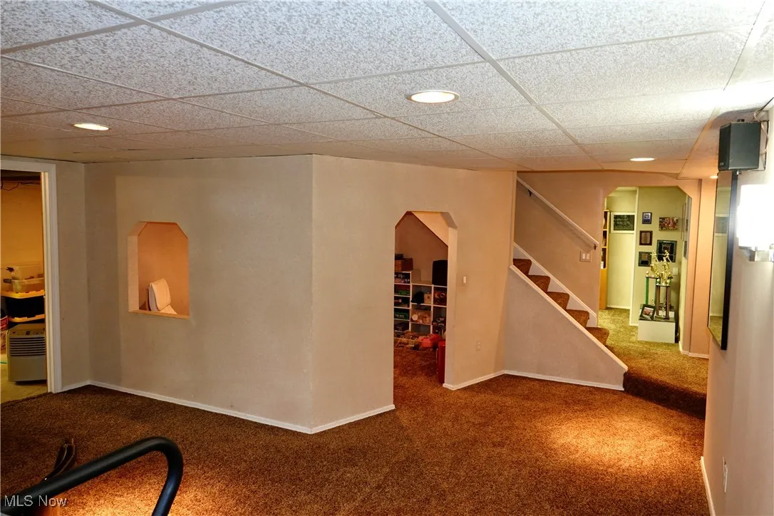 Carpeted spare room with stairs and a drop ceiling