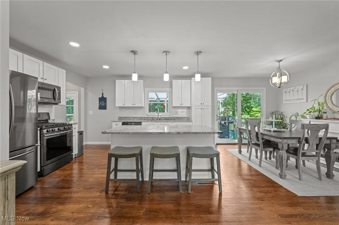 Kitchen with decorative light fixtures, white cabinetry, stainless steel appliances, recessed lighting, and light stone countertops