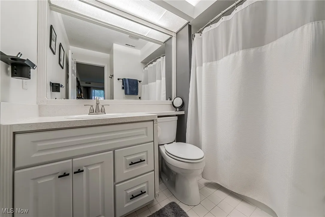 Full bathroom featuring light tile patterned flooring, vanity, and curtained shower