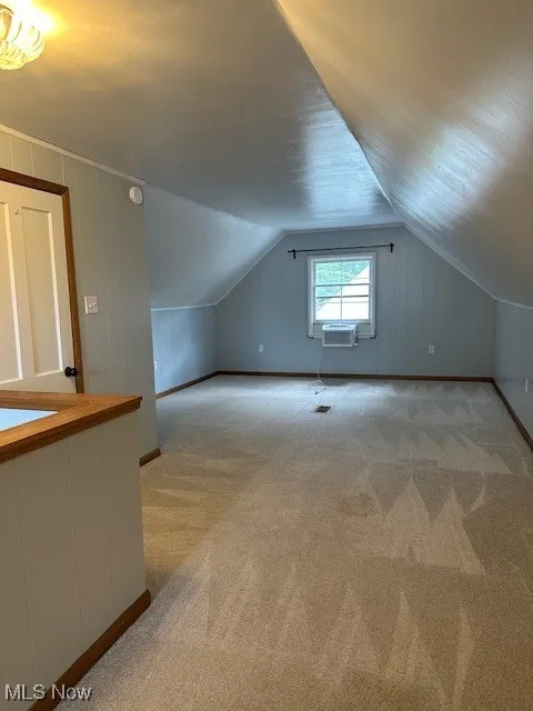 Additional living space featuring light colored carpet and lofted ceiling
