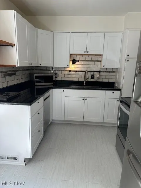 Kitchen with white cabinets, backsplash, and range