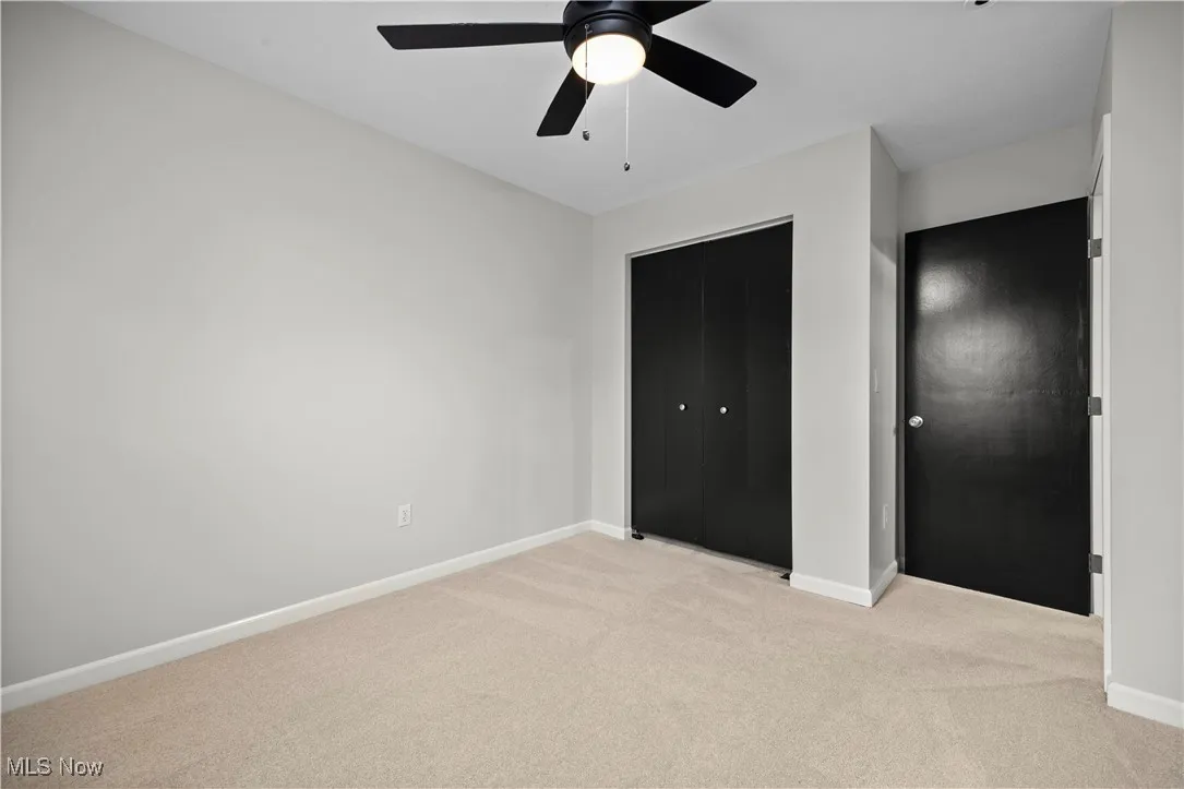 Unfurnished bedroom featuring light colored carpet, a ceiling fan, and a closet