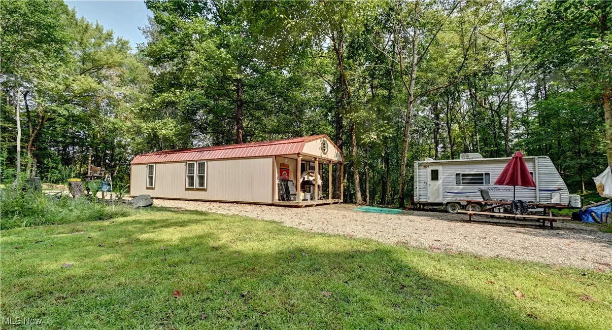 View of grassy yard with an outdoor structure and view of wooded area