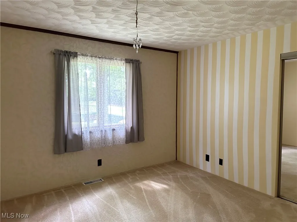 Unfurnished bedroom with carpet, wallpapered walls, and crown molding