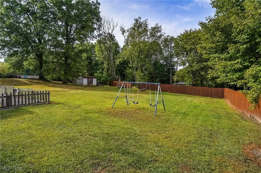 Fenced backyard with a playground and a shed