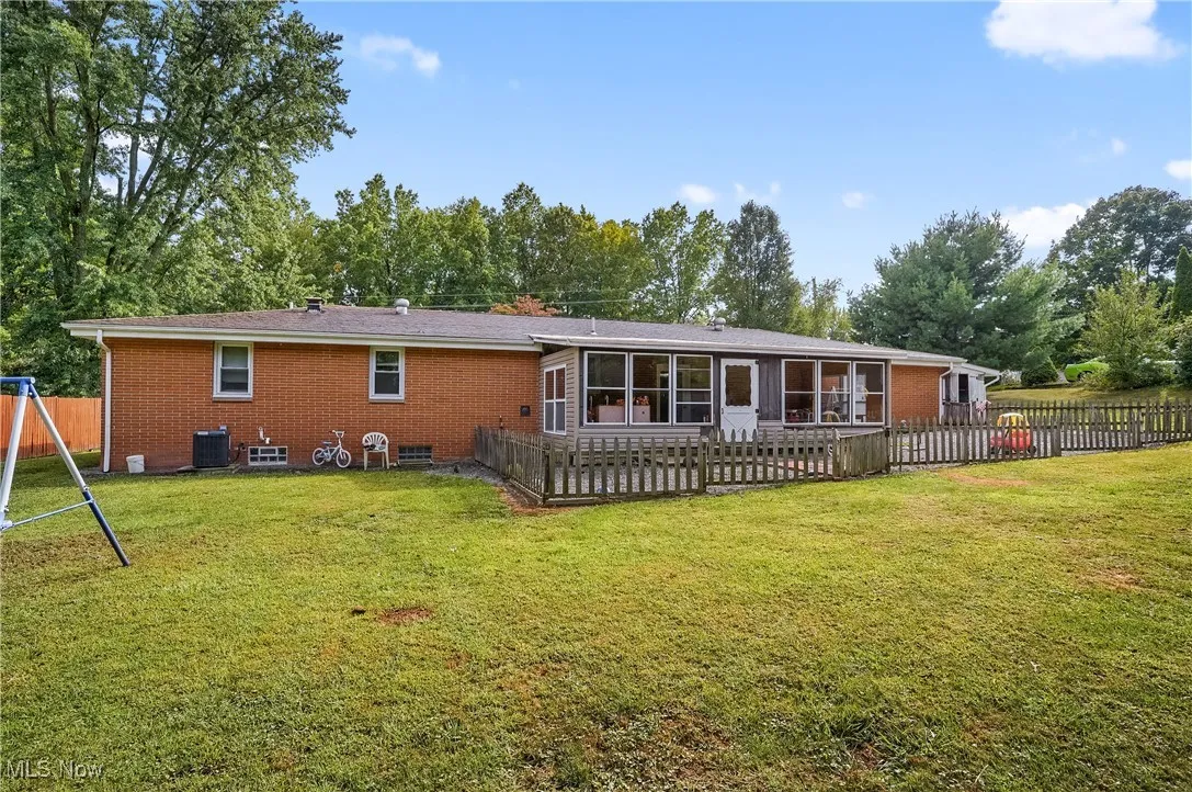 Rear view of property with brick siding and view of wooded area
