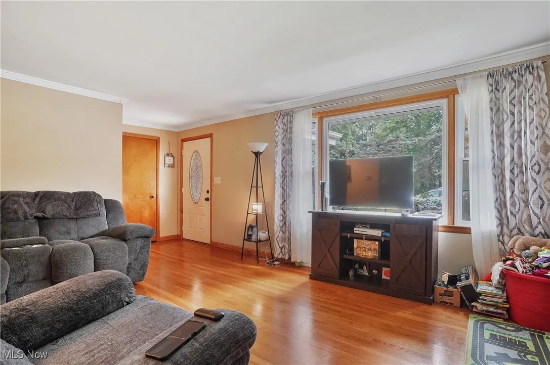 Living area with crown molding and wood finished floors