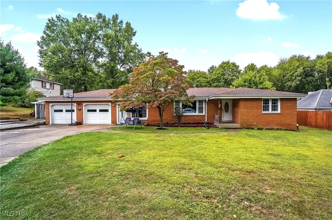 Ranch-style home with driveway, a front yard, brick siding, and an attached garage