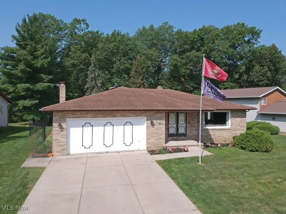 Single story home with a front yard, brick siding, a chimney, a shingled roof, and driveway