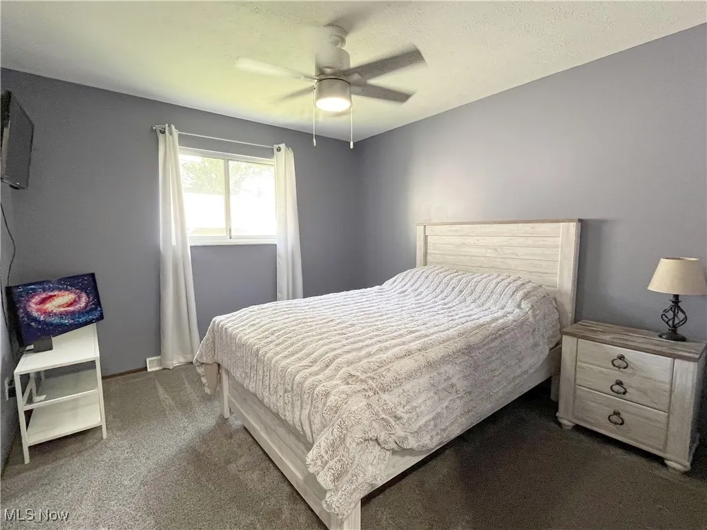 Carpeted bedroom with a textured ceiling and a ceiling fan
