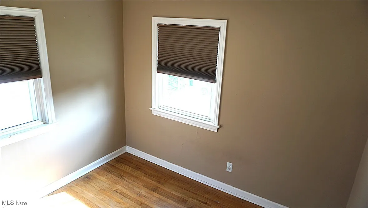 Spare room with baseboards and wood-type flooring