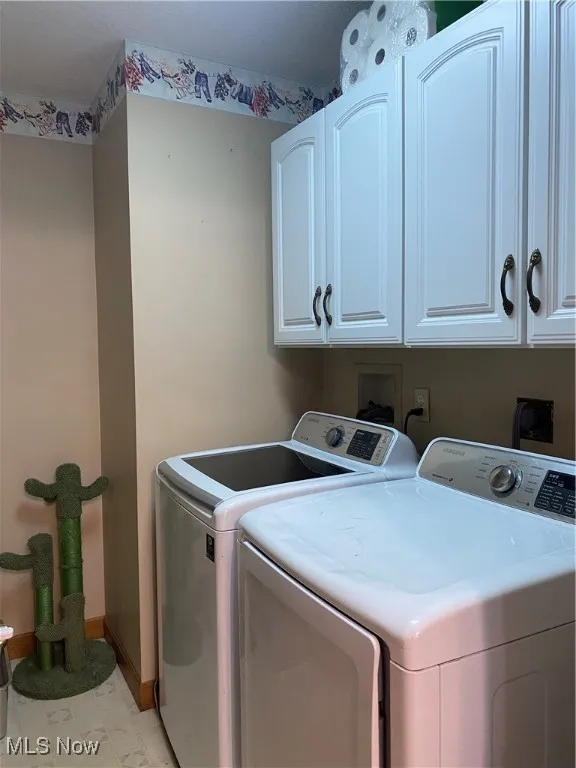 Laundry room featuring washing machine and clothes dryer and cabinet space