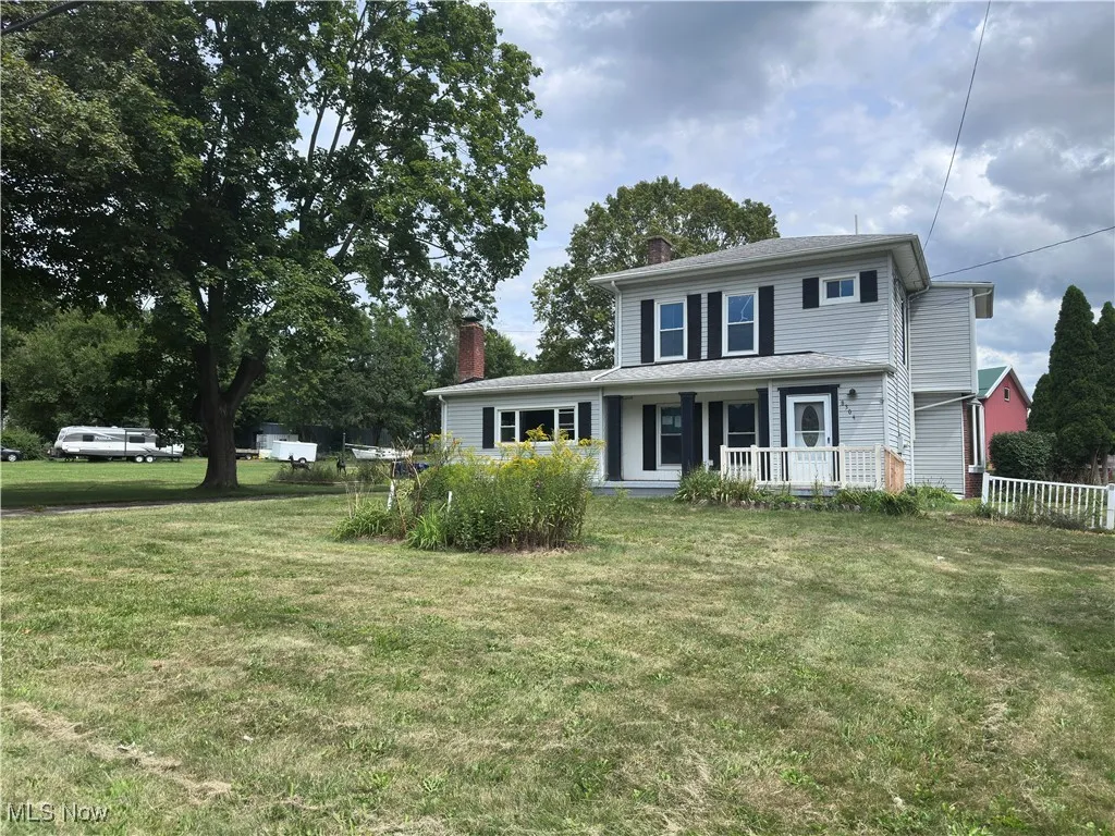 Traditional-style home featuring a chimney, a porch, and a front lawn