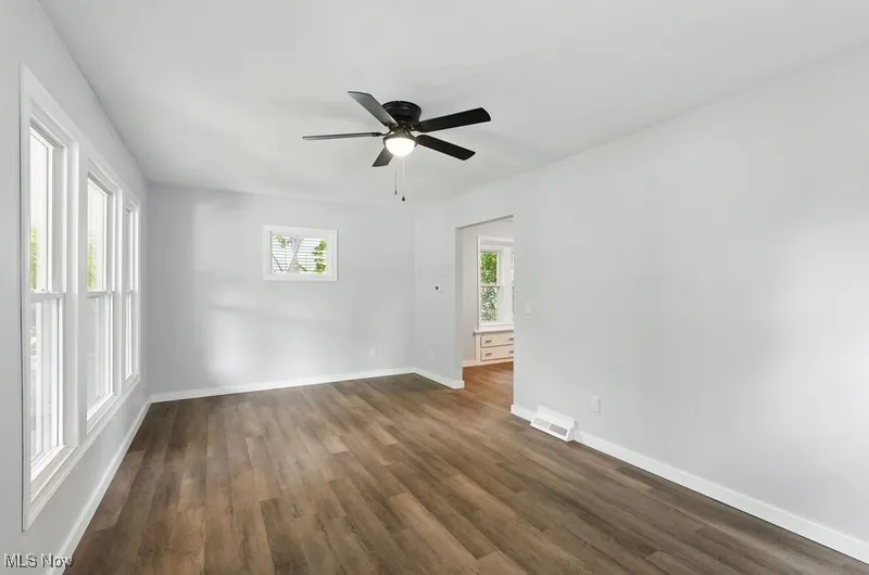 Unfurnished room with dark wood finished floors and a ceiling fan