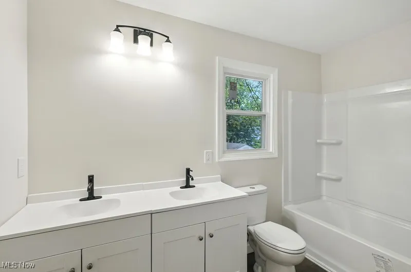 Full bathroom featuring double vanity and shower / tub combination