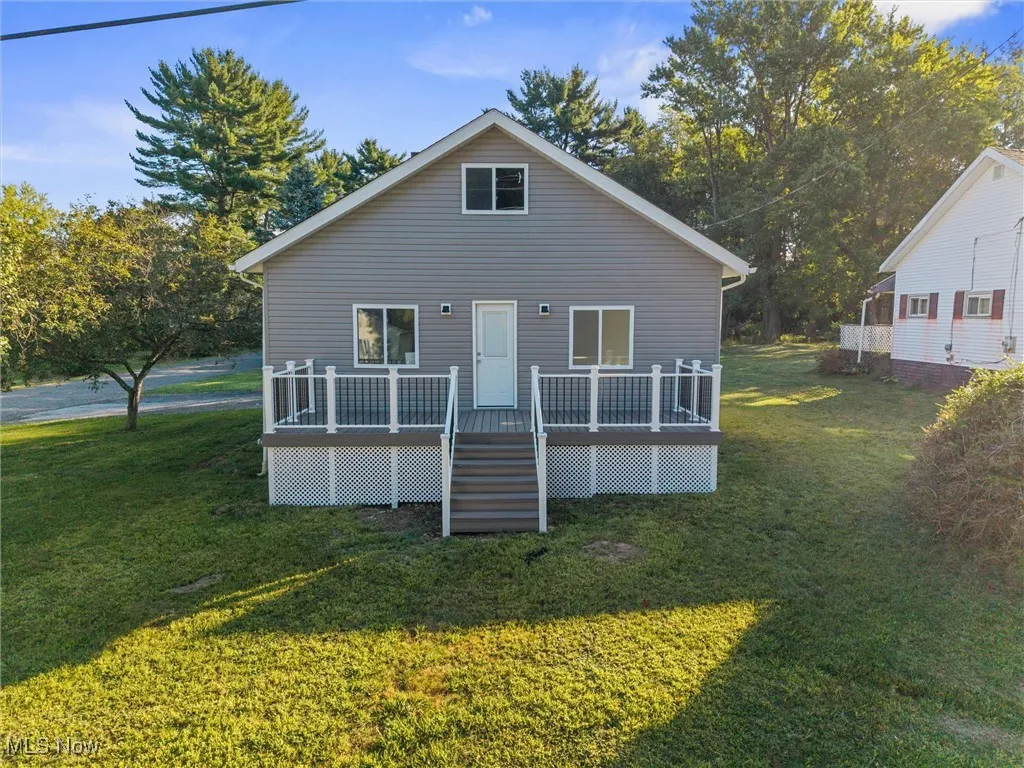 Rear view of house with a lawn, a deck, and stairway
