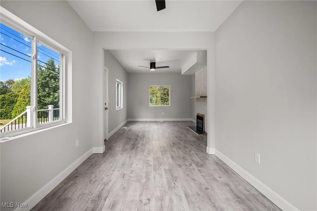 Unfurnished living room featuring light wood-style flooring, a large fireplace, and a ceiling fan