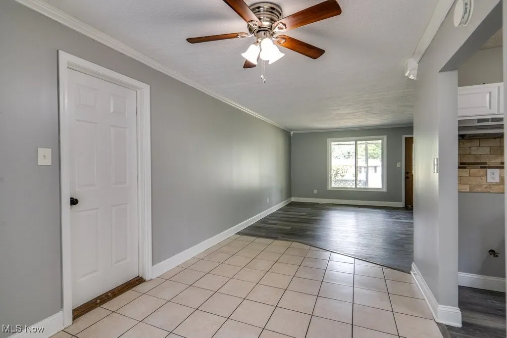 Unfurnished room featuring light tile patterned flooring, crown molding, a ceiling fan, a textured ceiling, and a smoke detector