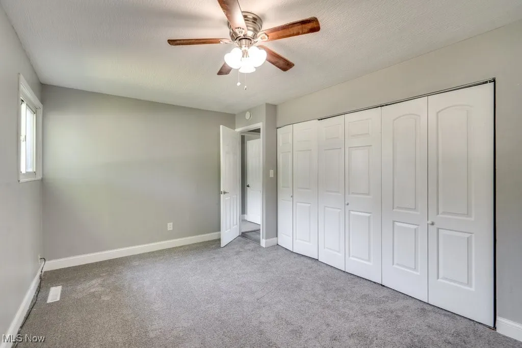 Unfurnished bedroom featuring carpet, a ceiling fan, a closet, and a textured ceiling