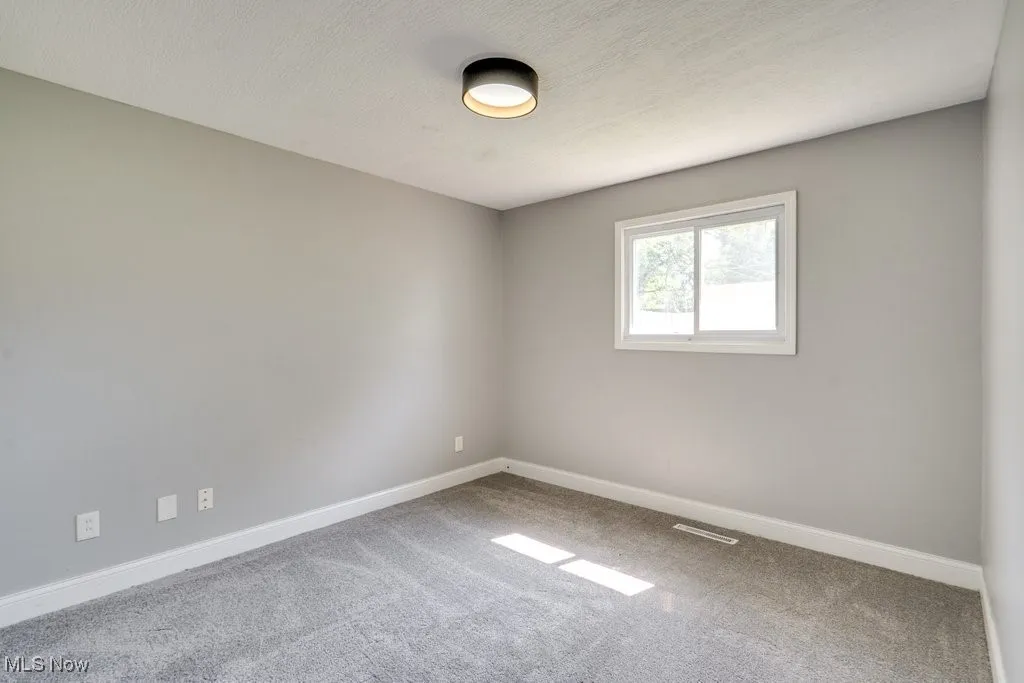 Empty room with carpet floors and a textured ceiling