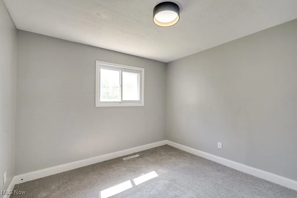 Empty room with carpet floors and a textured ceiling