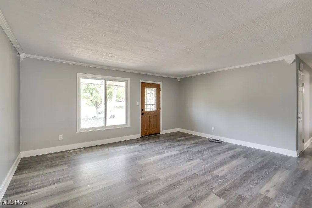 Foyer entrance featuring crown molding, light wood-style floors, and a textured ceiling