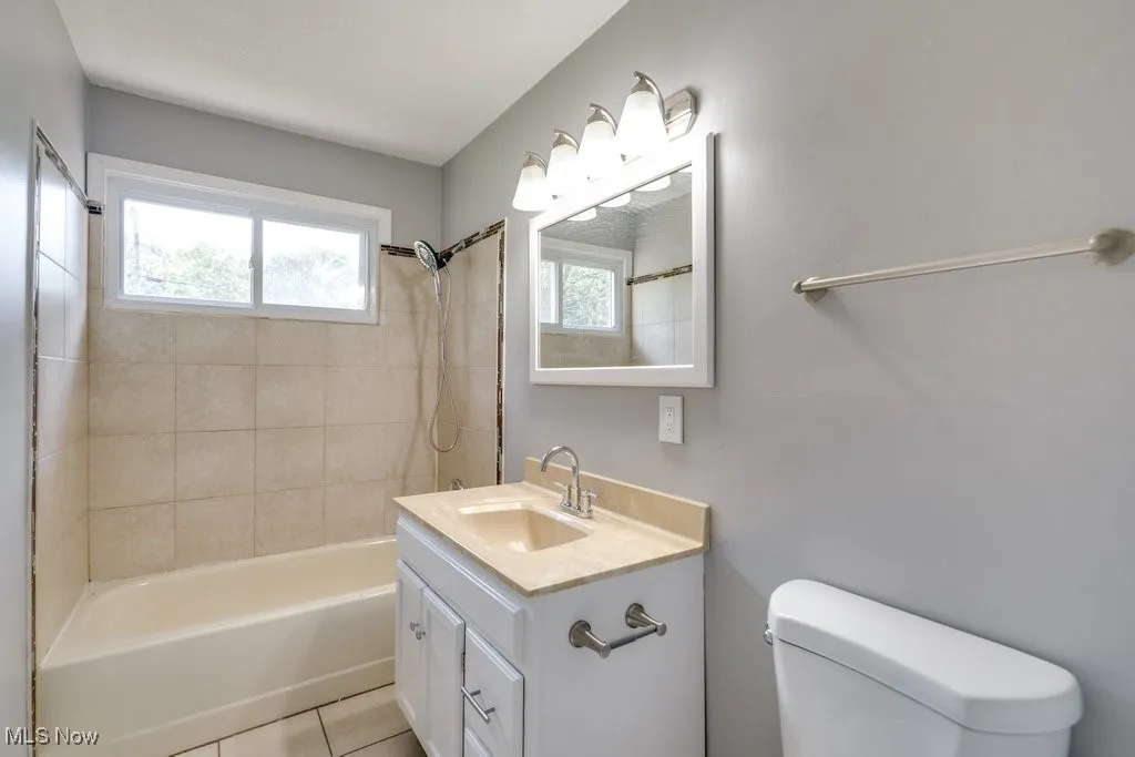 Bathroom featuring vanity, shower / tub combination, and light tile patterned floors