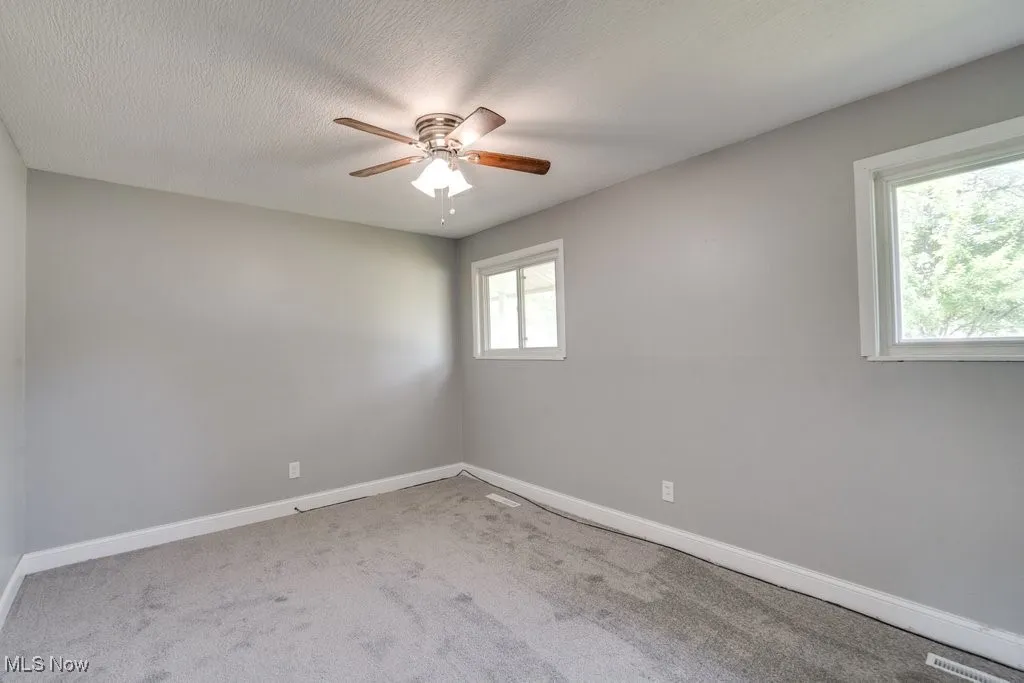 Carpeted spare room featuring ceiling fan and a textured ceiling