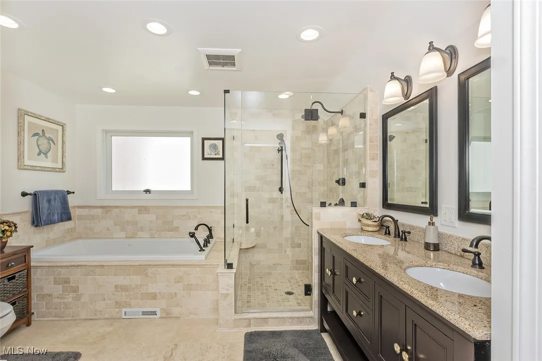 Gorgeous full bathroom with Travertine stone tile, his and hers sinks and a jetted tub