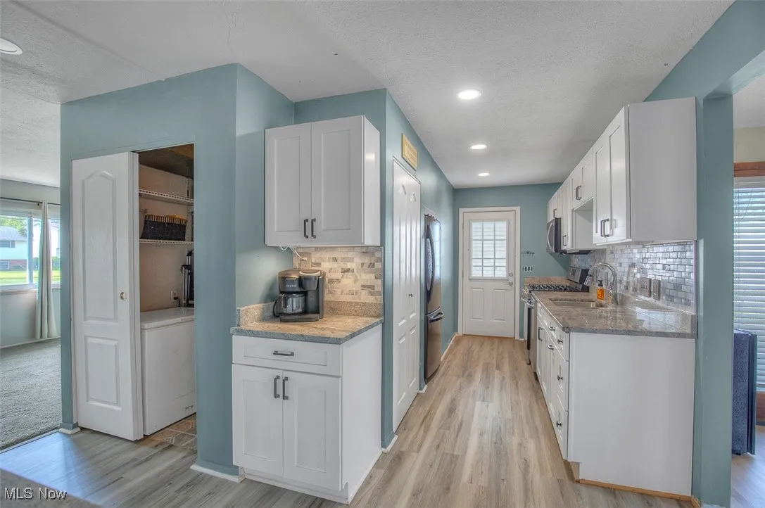 Kitchen featuring white cabinets, light wood finished floors, a textured ceiling, and recessed lighting