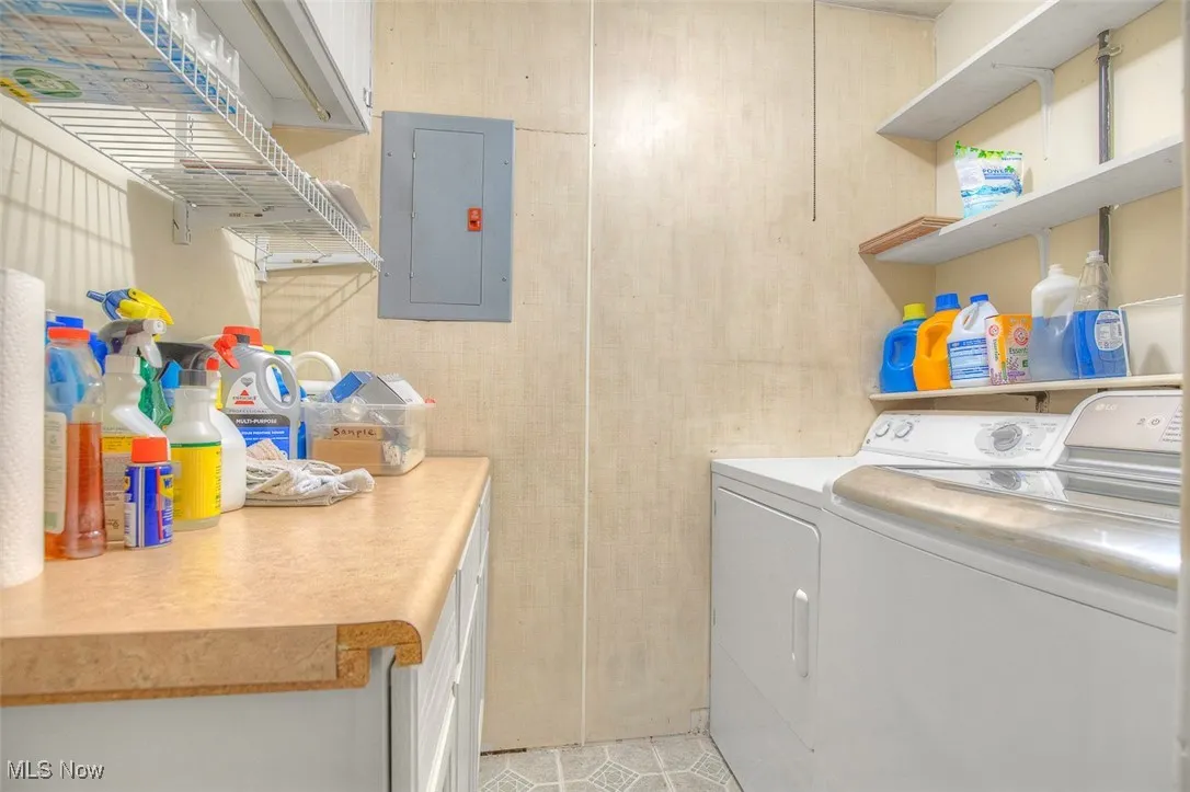 Laundry room with electric panel, separate washer and dryer, cabinet space, and light tile patterned floors