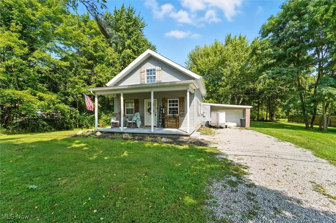 View of front of home featuring a front yard, a porch, and gravel driveway