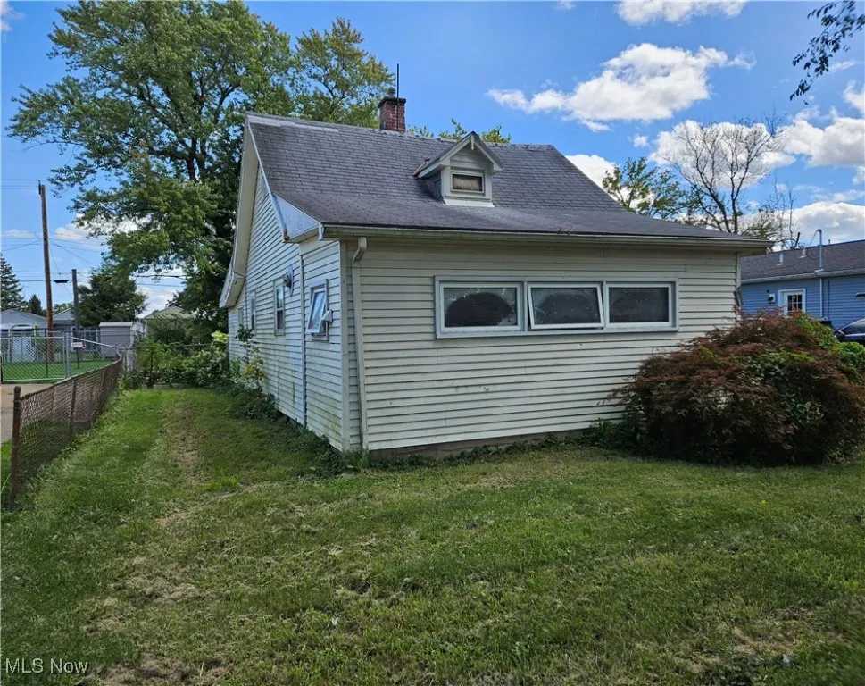 View of home's exterior featuring a chimney and a shingled roof
