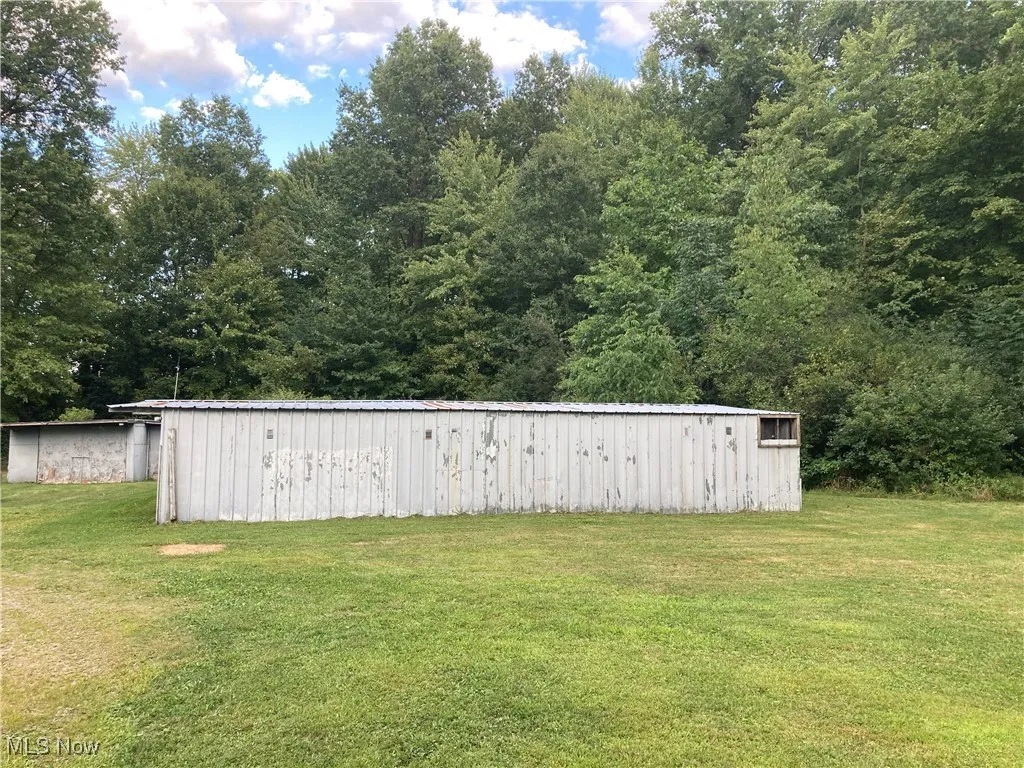 View of grassy yard featuring a pole building and an outbuilding
