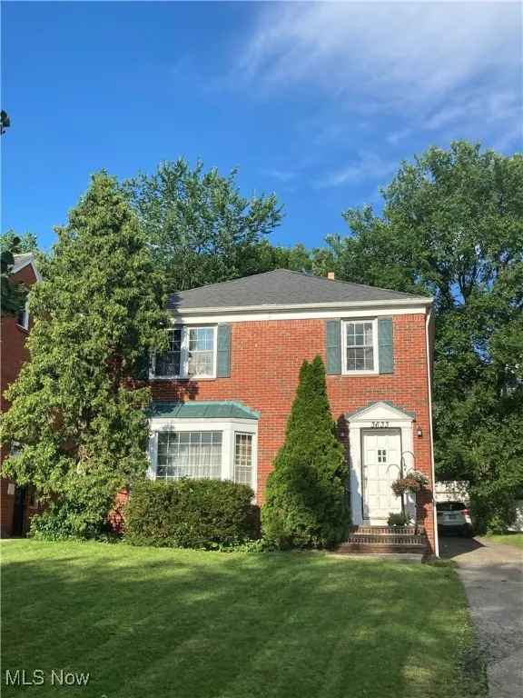 Colonial-style house with a front yard and brick siding